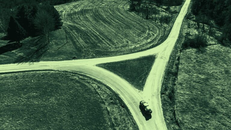 Luchtfoto van een splitsing in een landweg met een auto ervoor