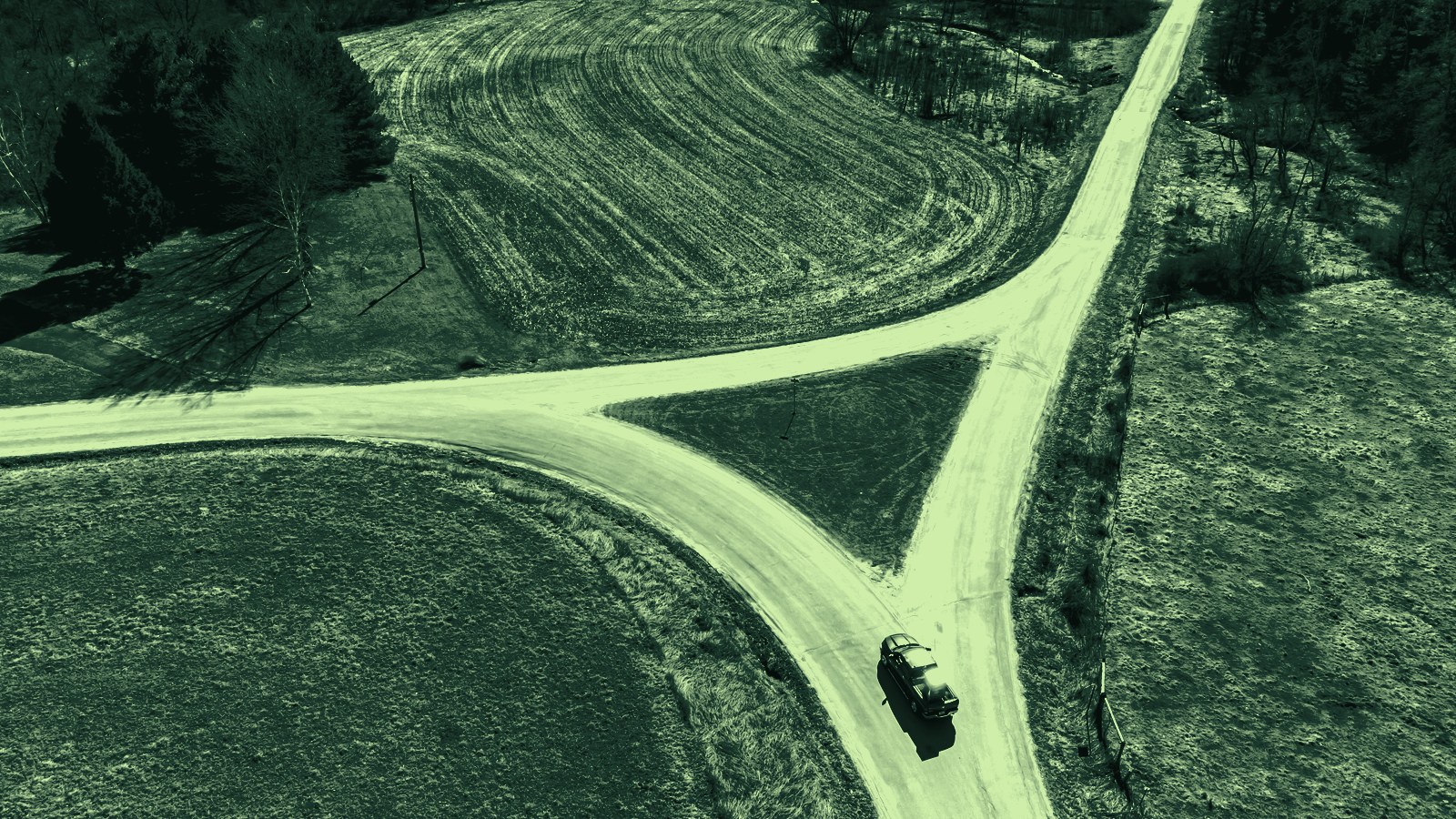 Luchtfoto van een splitsing in een landweg met een auto ervoor