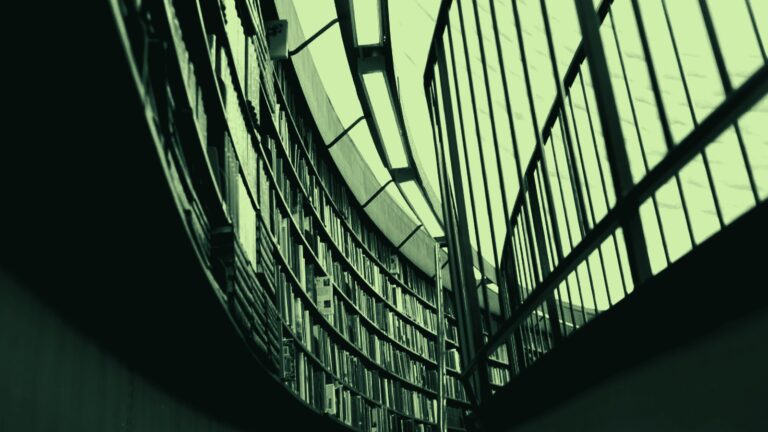 Gebogen boekenwand in een bibliotheek onder een glazen dak